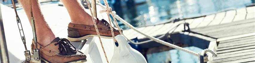 sailor attaching fenders to his yacht in marina 